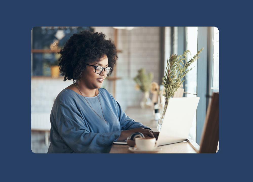 A woman with glasses looking at a computer while sitting at a desk