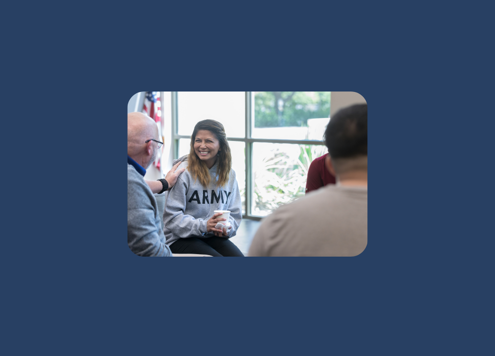 woman with an army hoodie and coffee talking to a man